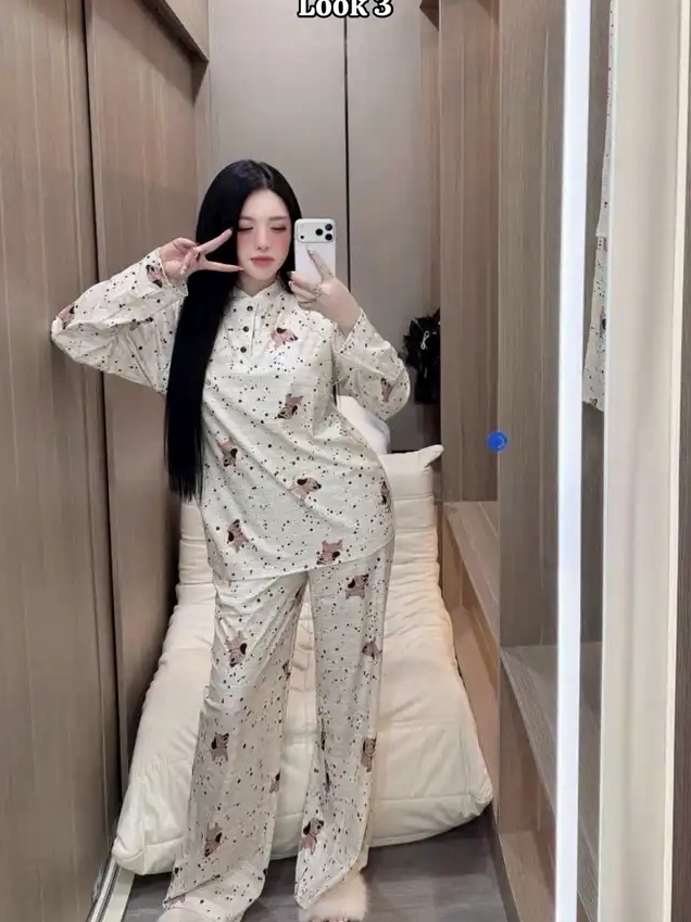 Một cô gái chụp ảnh selfie trong gương mặc bộ đồ ngủ màu kem in họa tiết động vật nhỏ tạo dáng chữ V